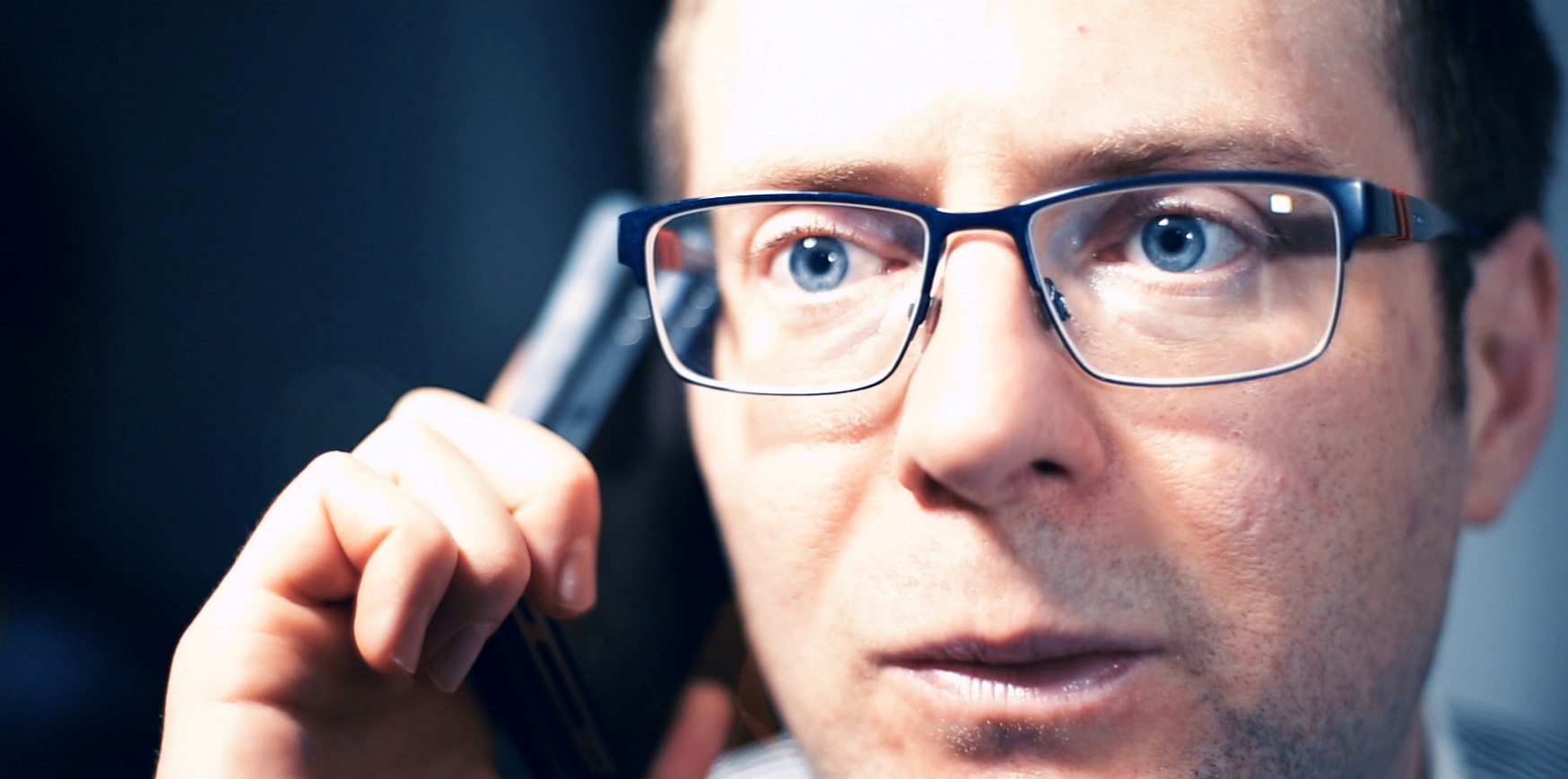 Arek Zasowski portraying Spencer in Chinese Angel film, intense close-up holding a phone, dramatic lighting highlighting expressive blue eyes and emotional focus.